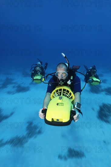 Divers with diver propulsion vehicles exploring a coral reef