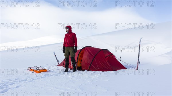 Ski tourer with tent in the snow