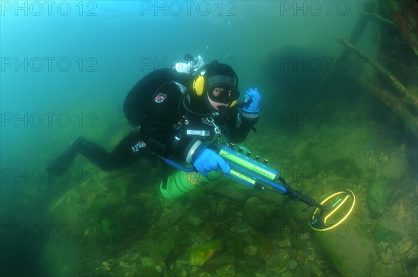 Diver with metal detector searching for underwater treasure