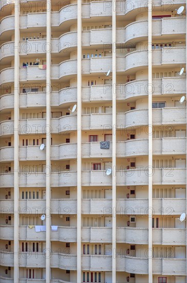Facade of a skyscraper with satellite dishes on balconies