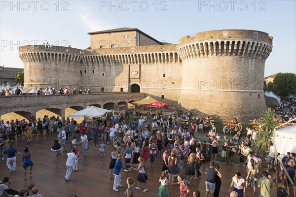 People dancing in the festival grounds in front of Fortress Rocca Roveresca