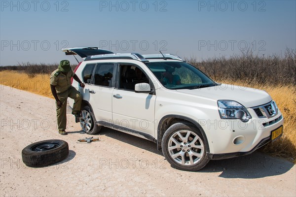 African gamekeeper changing a tire of an SUV