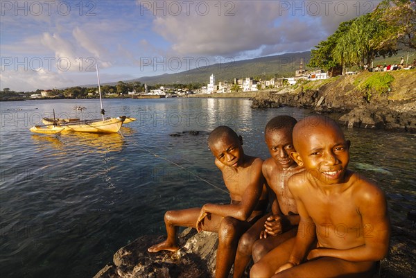 Three boys sitting on a rock