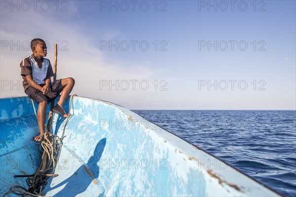 Boy on a fishing boat looking out to the sea