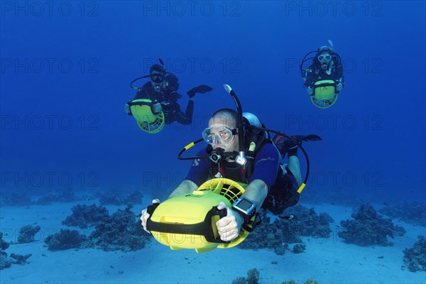 Divers with diver propulsion vehicles exploring a coral reef