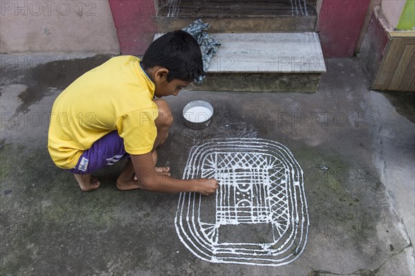 Boy painting a traditional Rangoli