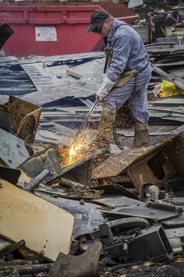 A man cutting up an armored vehicle type Marder with a torch