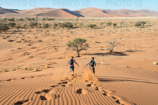 Two teens running down a dune