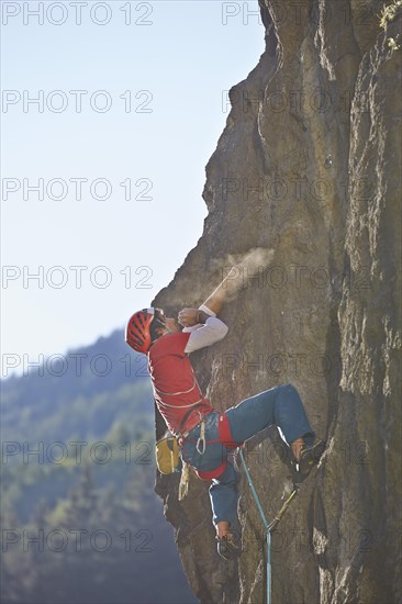 Sport climber wearing a helmet climbing a rock face