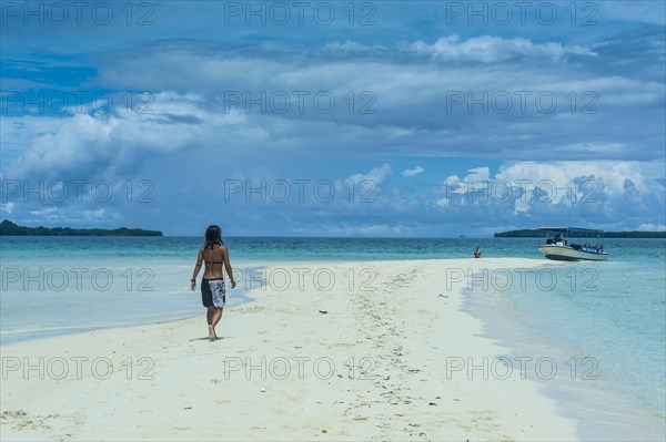 Tourist walking on a sand strip at low tide