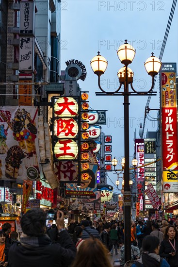 Crowd crowded in pedestrian zone with lots of illuminated advertising for restaurants and shopping centers