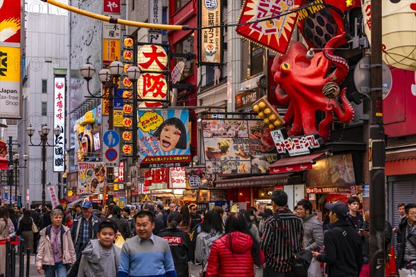 Crowd crowded in pedestrian zone with lots of illuminated advertising for restaurants and shopping centers