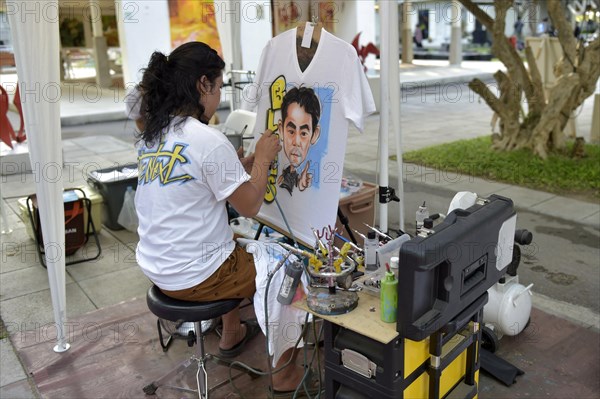 Woman airbrushing a portrait on a T-shirt