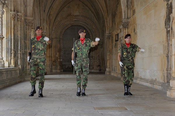 Three Portuguese soldiers with guns in the cloister at the changing of the guard for the grave of an unknown soldier