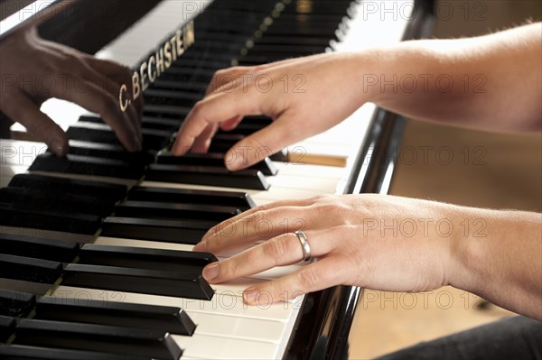 Woman's hands playing a Bechstein grand piano