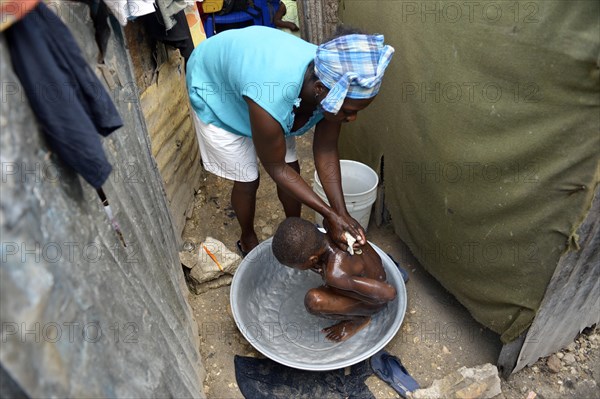 Woman washing a boy outside her hut