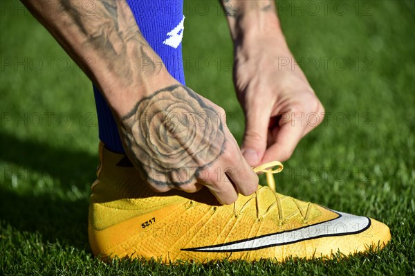 Football player tying the laces of his soccer shoes