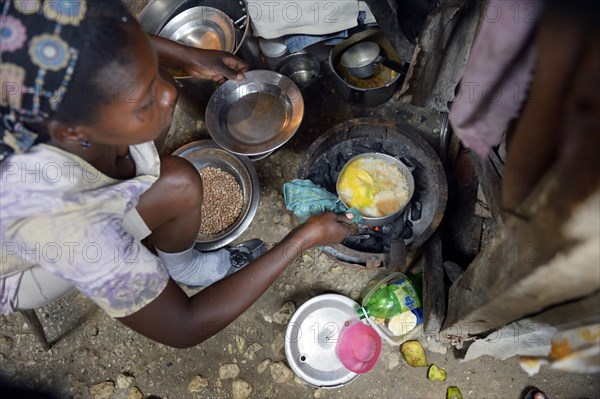 Woman cooking in the improvised kitchen of a ramshackle hut