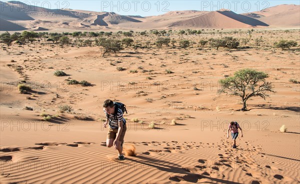 Two teens running up a dune