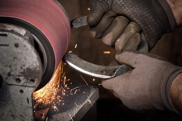 Blacksmith grinding a horseshoe