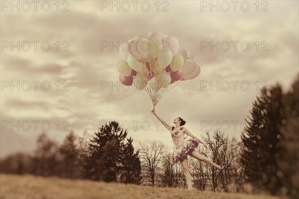 Young woman holding lots of balloons