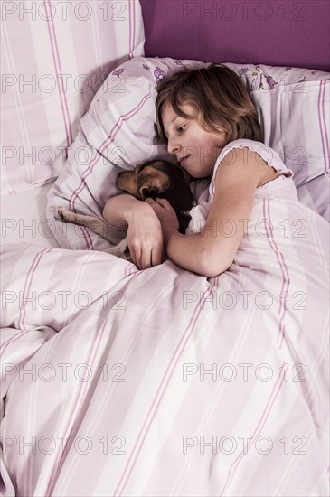 Girl lying in bed with a Danish Swedish Farmdog