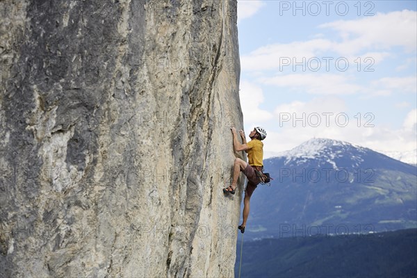 Freeclimber with helmet climbing on a rock face