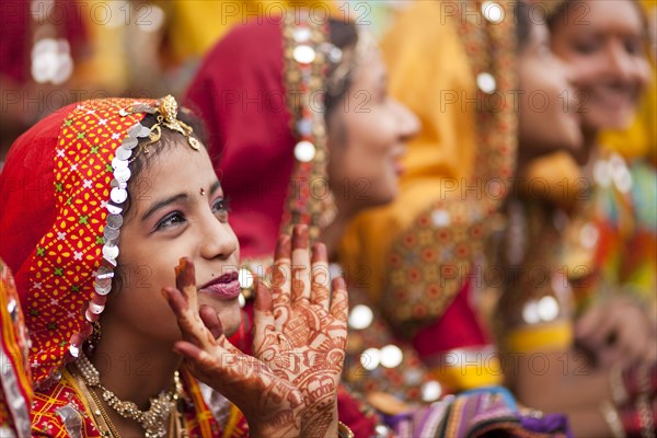 Young women in typical colourful traditional Rajasthani costume and henna painted hands at the camel market and livestock market