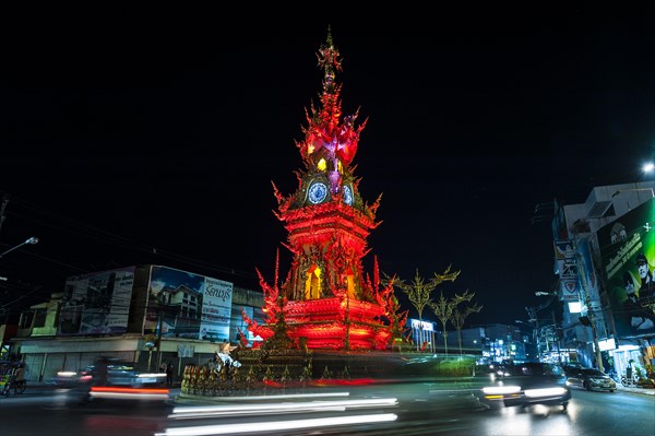 Colourfully illuminated Clock Tower at night with light trails of vehicles