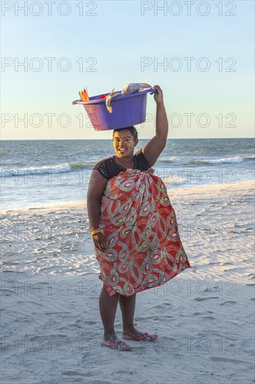 Malagasy woman carrying fish in a tub on her head