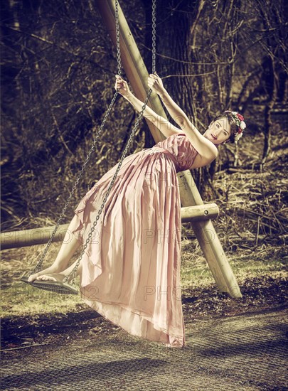 Young woman with flowers in her hair standing on a swing