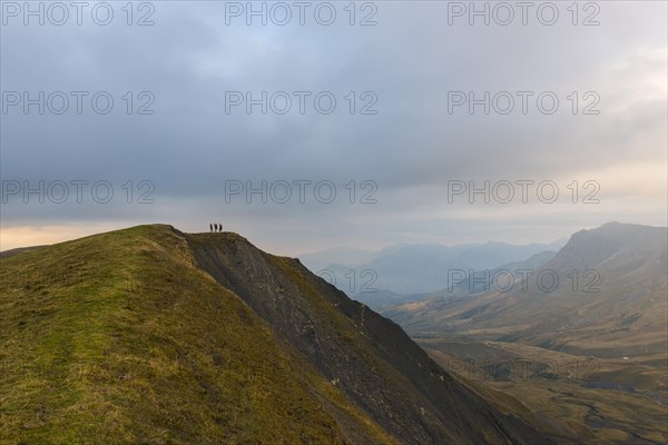 Three hikers on the ridge of a mountain in the Ecrins at dusk