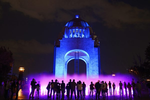People watching the light show and fountains in front of the Monument to the Revolution