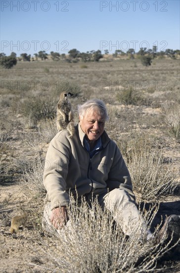 Sir David Attenborough with meerkat on shoulder for BBC series The Life of Mammals