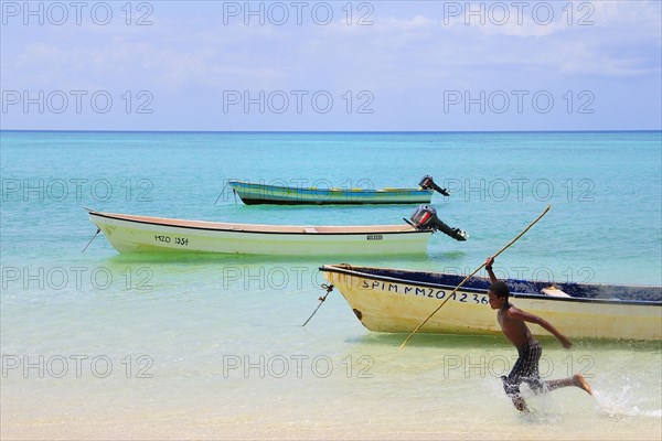 Boy with spear chasing fish in the shallow water