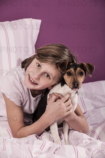 Girl lying in bed with a Danish Swedish Farmdog