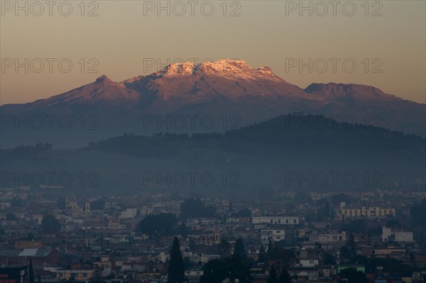 The volcano Iztaccihuatl in early morning light with city