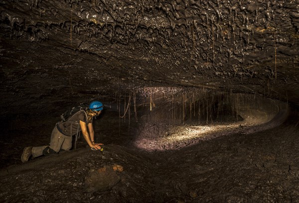 Tourist in a subterranean lava tube created by an eruption of the Piton de la Fournaise volcano