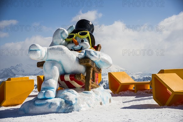 Snowman with sunglasses and a top hat sitting in a deck chair