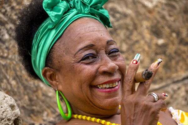 Senior Cuban woman with the Cuban flag painted on her fingernail smoking a Cuban cigar