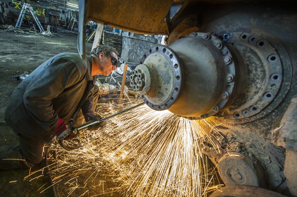 A man cutting up an armored vehicle type Marder with a torch