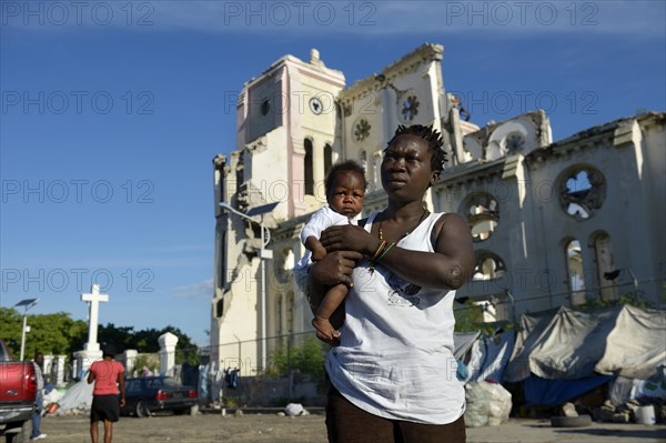 Woman holding a child in front of the ruins of the cathedral