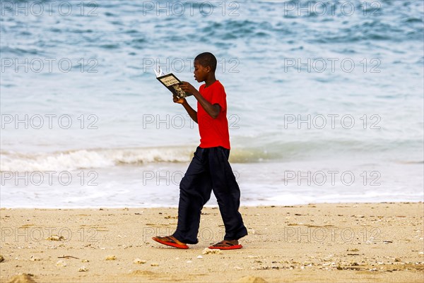 School boy walking along the beach