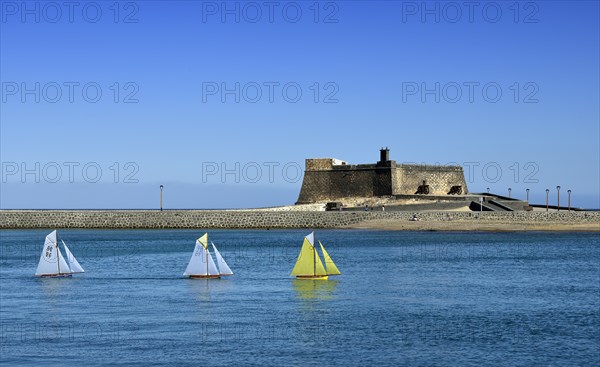 Model sailing boats in a regatta in front of the fort Castillo de San Gabriel