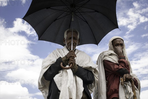 Shepherds protect themselves with an umbrella from the scorching sun