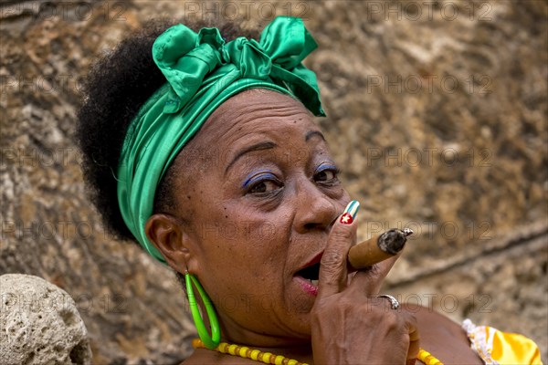 Senior Cuban woman with the Cuban flag painted on her fingernail smoking a Cuban cigar