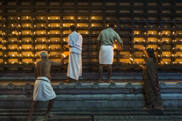 Oil lamps being lit in niches on the outer wall of the temple for the Hindu fire ceremony Aarti