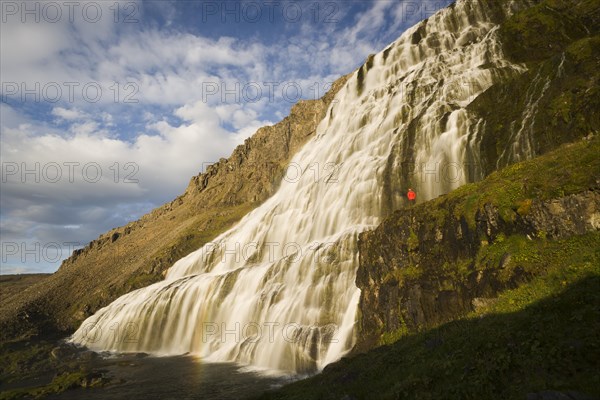 Person standing in front of the Dynjandi waterfall