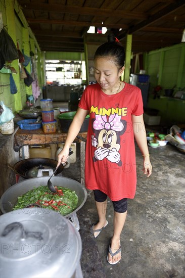 Young woman cooking in a simple restaurant