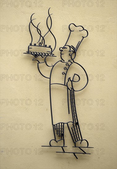 Stylized baker with fragrant cake at a bakery house wall